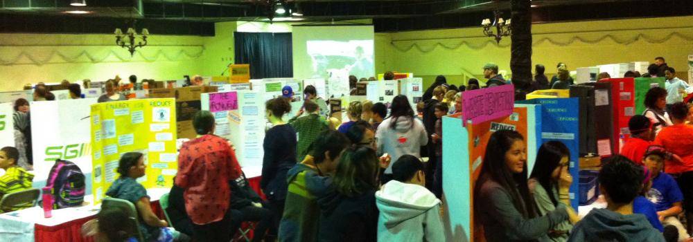 picture of a busy science fair with teens and adults