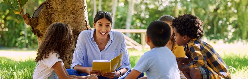 Teacher reads a book to students outside