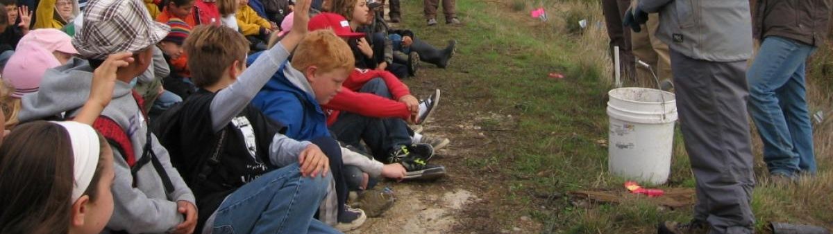 Student's raising their hands with questions while learning outside. 