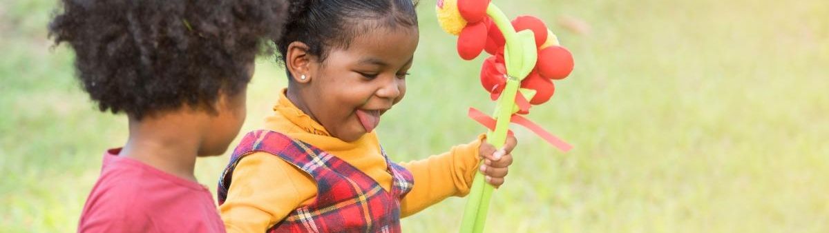 Two girls outside, one of them holding flowers.
