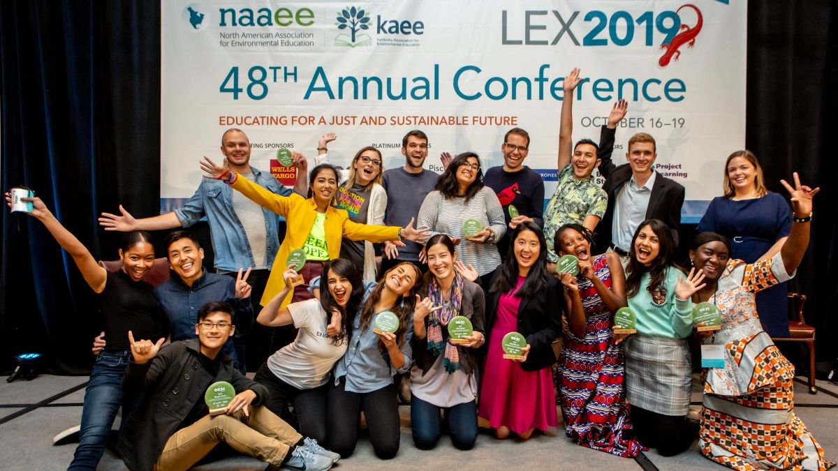 EE 30 Under 30 smiling and posing in front of the NAAEE 2019 Conference banner.